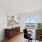 Bright and modern home office with a scenic city view, sleek wooden desk, and minimalist artwork