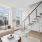 Chic living room with modern staircase, large windows, elegant sofa, and stylish decor.