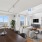 Bright and modern living room with large windows showcasing spectacular views, featuring a cozy seating area, sleek TV setup, and a stylish dining table